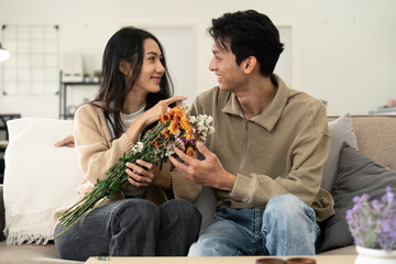 Asian handsome man show the love and give flowers to his girlfriend in living room on valentine...