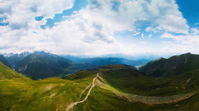 Aerial view at the Koruldi lakes. Green hills, high mountain pastures. Summer day. in the background are the snowy peaks of the Caucasus Mountains. High resolution panorama