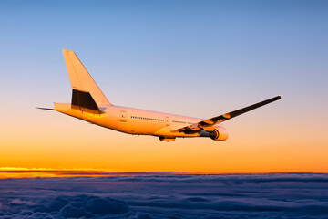 White wide body passenger jetliner fly in the sunset sky