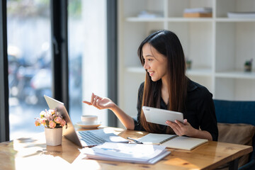 Business woman using laptop and holding digital tablet. Video conference. Searching for information.