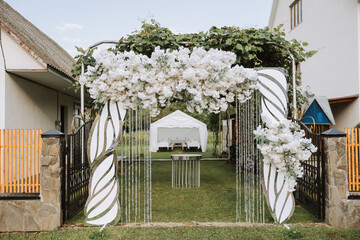 The photo zone at a wedding or birthday celebration is decorated with flowers and illuminated by...
