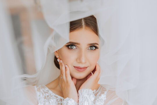 Portrait of the bride in the hotel room. A beautiful young girl is dressed in a white wedding dress. Modern wedding hairstyle. Natural makeup.