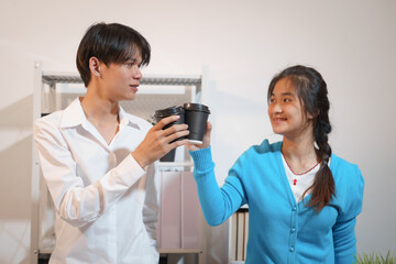 An Asian male consultant and an African American female intern sit at a table with laptops doing paperwork together to discuss a project's financial reports. Company business collaboration concept