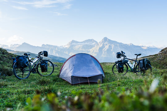 Camp on a bike travel with two loaded bikes with panniers and a tent in between on a mountain pass in the Swiss alps
