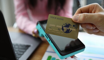 Male fingers hold credit card above terminal. Repayment loan obligations during quarantine period....