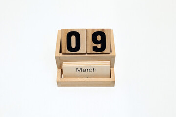 Close up of a wooden perpetual calendar showing the 9th of March. Shot close up isolated on a white background