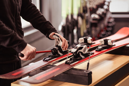 Skis for Rent. Ski Rental Service. Ski Repair Shop Worker Adjust the Bindings and Equipment with Screwdriver. Ski Workshop Service.