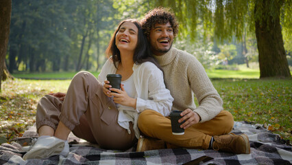 Happy smiling multiethnic married couple in love man woman boyfriend girlfriend having picnic sit...