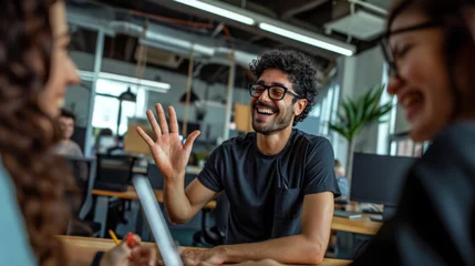 Fotobehang Young man with an afro hairstyle and glasses is smiling and giving a high-five in a casual office or coworking space environment. © MP Studio