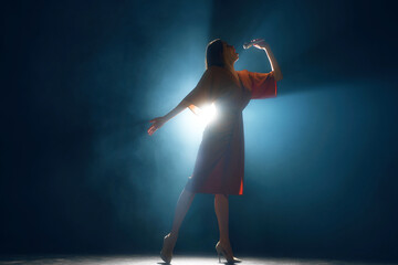 Female vocalist in expressive pose, silhouetted against dark blue backdrop with ambient light...