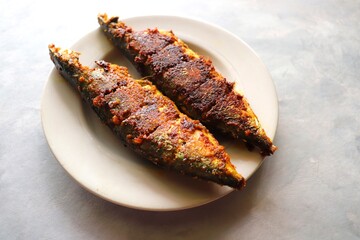Indian Mackerel fish fry. Bangda Rava fry. whole Fried fish served on a white vintage plate. also known as talalele bangde in Marathi. Copy space.
