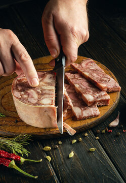 Prepare a quick and tasty snack. A man hands use a knife to cut brawn from meat on a cutting board