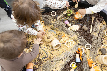 unrecognizable little children manipulating natural materials on a work table in kindergarten
