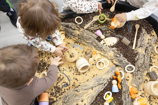 unrecognizable little children manipulating natural materials on a work table in kindergarten - Powered by Adobe