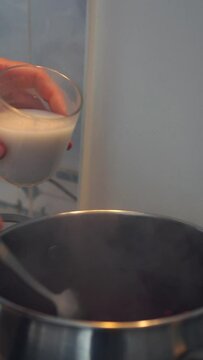 Pouring Milk Into a Pot with fruit drink, making Kissel 