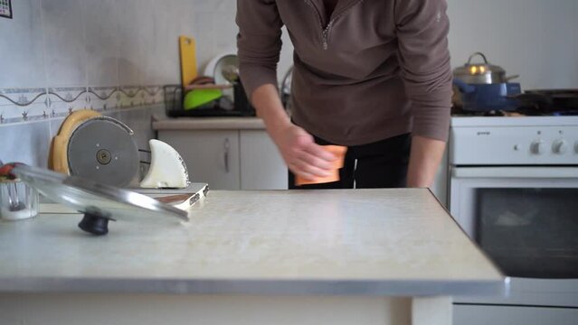 Woman hand wiping an orange kitchen counter with a cloth.