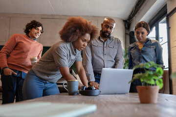 Team standing up looking at a laptop together in a casual meeting