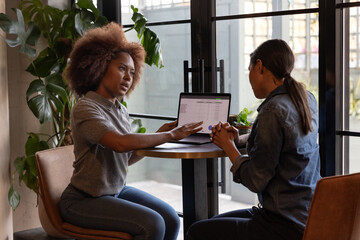 Two businesswomen looking at data together in a casual meeting