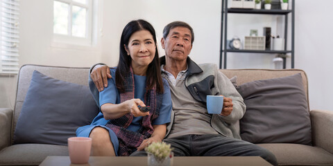Senior couple watching tv and sofa in relax for movie or series in living room at home. Elderly man...