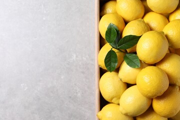 Fresh lemons in wooden crate on grey table, top view. Space for text