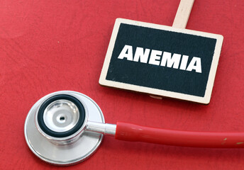 ANEMIA word on a small chalk board next to a stethoscope on a red background.