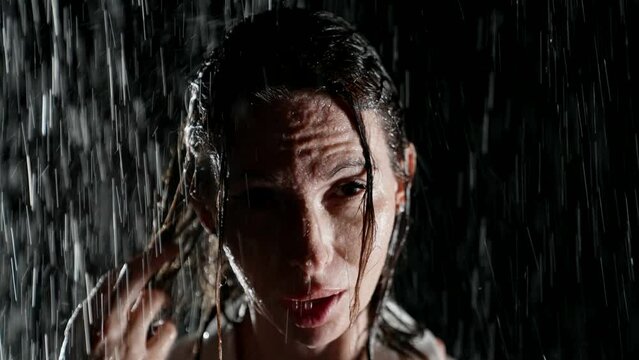 Portrait of a woman soaked in the night rain, in a white shirt. Her gaze is filled with steadfast determination, the embodiment of strength and femininity in one.
