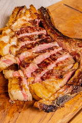 Bistecca di manzo al sangue cotta sulla brace, scaloppata e poggiata su un tagliere di legno in una braceria