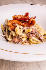 Fusilli freschi con speck, pancetta croccante e formaggio serviti come primo piatto in un ristorante
