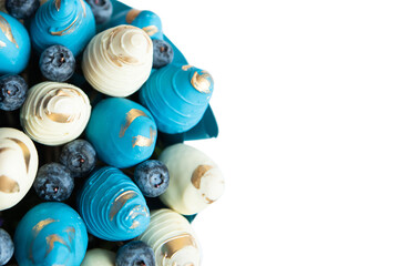 Fresh strawberry covered by blue and white chocolate with berries designed as bouquet. Background.