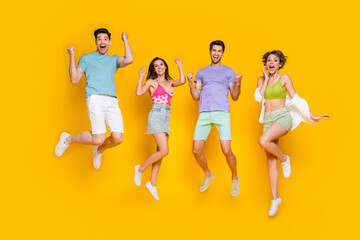 Full body photo of cheerful people buddies jump with raised fists winning isolated over bright color background - obrazy, fototapety, plakaty