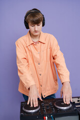 Teenage DJ playing music on a turntable isolation in stylish clothes on purple background
