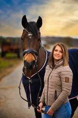 Woman with horse in portraits on a path with dramatic sky in the background.