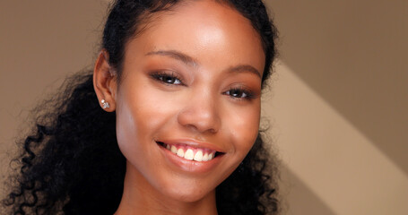 Portrait of a black girl with curly hair, soft makeup and perfect skin. Beautiful face of young black woman with natural skin.