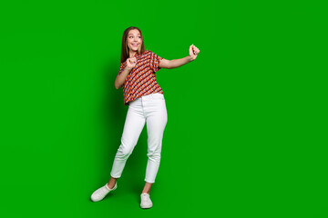 Fototapeta na wymiar Full size photo of satisfied teenager wear print blouse white trousers dancing look empty space isolated on vibrant green color background