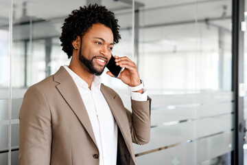 Businessman is engaged in a phone conversation, discussing important business matters, with a backdrop of a contemporary office space, having positive dialogue, sealing deal or forming new partnership