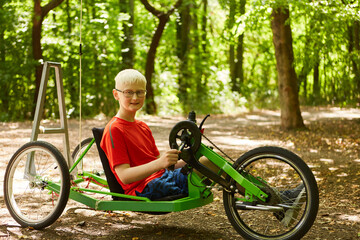Handicapped boy with prsthetic limb riding in recumbent bike