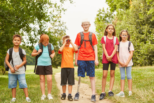 Group of children with backpacks walking on hiking trail in summer