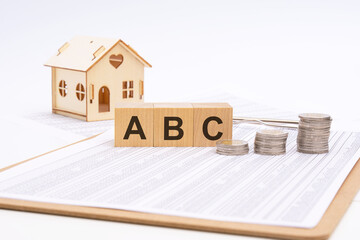 cubes form the text ABC. on a light background there is a row of cubes and a toy house in the background. finance and banking concept