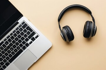 Headphone and laptop on beige background, technology concept.