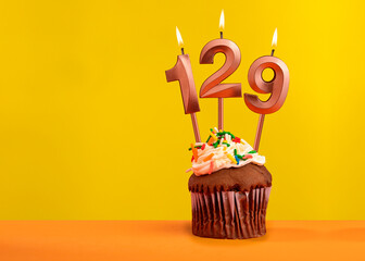 Number 129 birthday candle - Celebration on yellow background