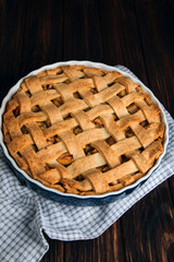 Apple pie in blue form on a dark wooden background with a gray kitchen towel. Ready pie. Top view