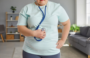 cropped portrait of a young fat overweight woman wearing sportswear standing at home and listening...