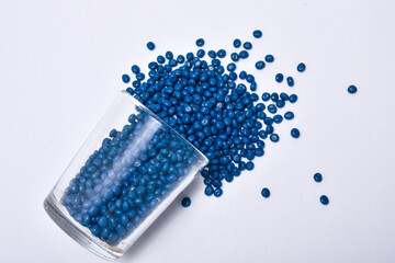 Navy blue masterbatch droplets spilling from a shot glass, isolated on a white background.  This...