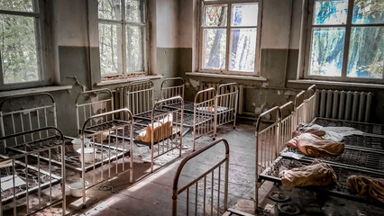 empty children's beds in an abandoned kindergarten house with peeling walls in Chernobyl