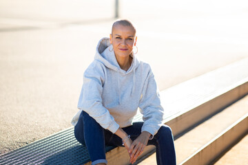 woman with shaved hair sitting outdoors on steps