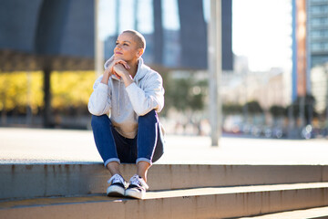 Full body woman with short hair sitting on steps