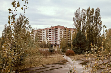 Fototapeta na wymiar street and houses among the trees in the empty deserted abandoned town of Pripyat in Ukraine