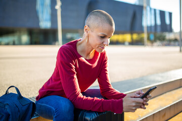 woman looking at mobile phone while sitting outdoors