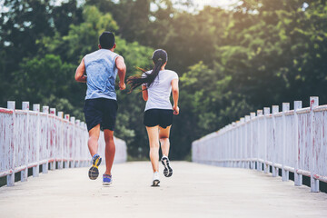 Couple running together on road across the bridge. Couple, fit runners fitness runners during...