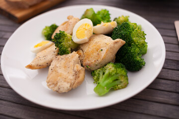 Pieces of fried chicken breast with boiled broccoli and quail eggs on plate for lunch